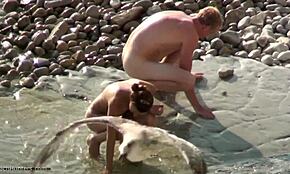 Amateur nude couple picking rocks on hidden beach cam