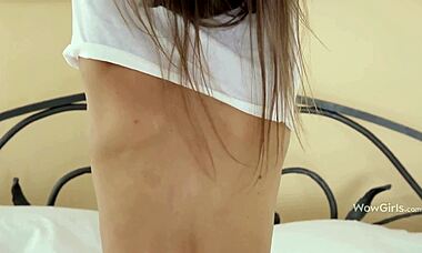 yo, check this dark-haired babe stripping on a big bed!